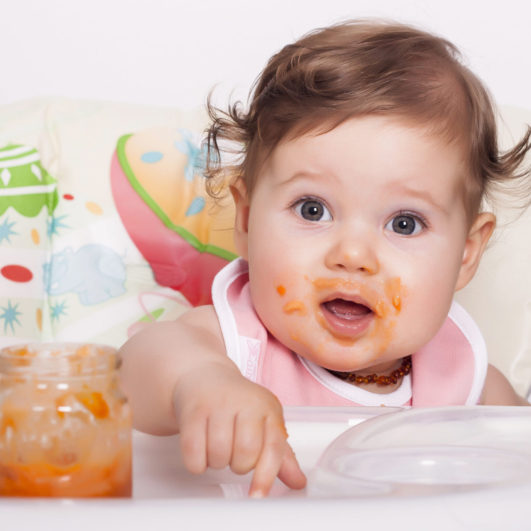 An adorable smudgy female baby eating her favorite food
